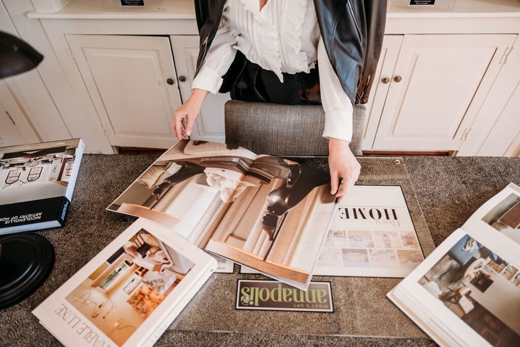 Interior designer reviewing luxury home design magazines at a styled workspace, showcasing Lynn Madyson Interiors’ curated and elevated design process.