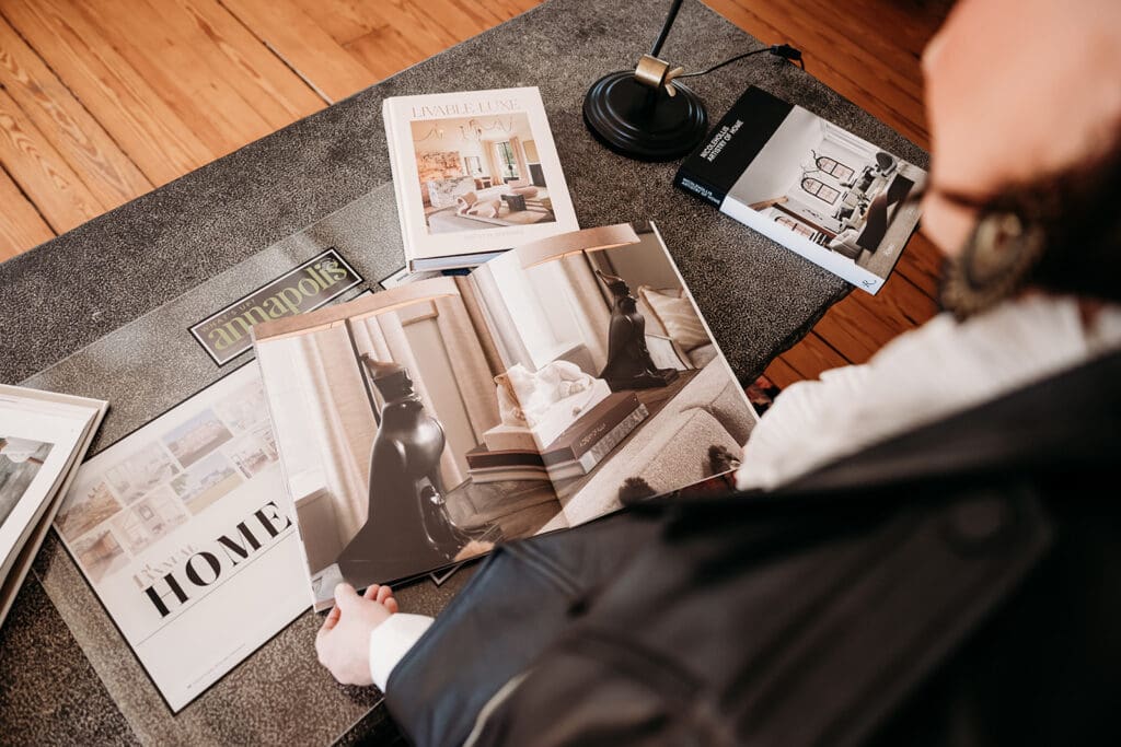Overhead view of an interior designer reviewing luxury home design magazines and curated decor references on a styled workspace, reflecting Lynn Madyson Interiors’ elevated and intentional design process.